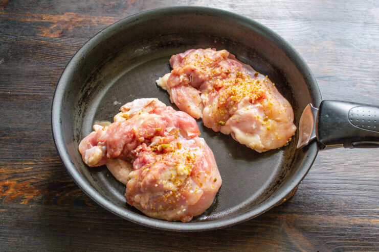 Searing Chicken Thighs Skin-Side Down for a Crispy Skin Seasoned chicken thighs searing skin-side down in a hot, non-stick skillet.