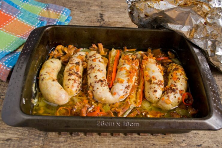 The cooked chicken sausages and mushrooms in the baking dish after being removed from the oven.