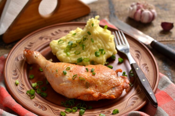 A plate of perfectly pan-fried chicken legs, golden and crispy, garnished with fresh herbs.