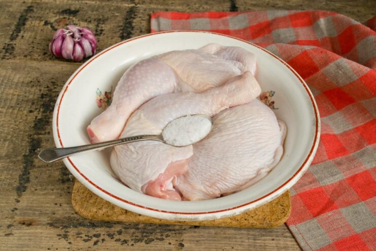 Step 3: Seasoning the chicken generously with salt Seasoning raw chicken legs with coarse salt to flavor the meat.