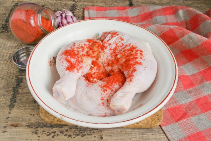 Step 5: Coating the chicken with sweet paprika for color and flavor Chicken legs being coated with red sweet paprika powder for a vibrant crust.