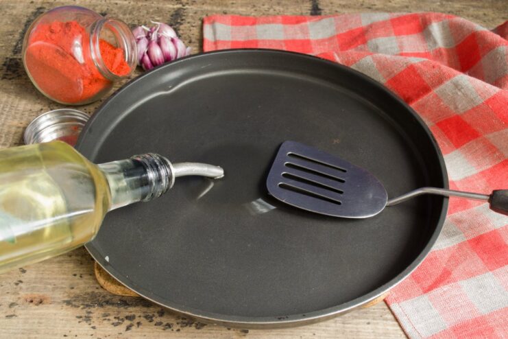 Step 6: Preheating the skillet with oil before frying Vegetable oil heating up in a black non-stick frying pan on the stove.