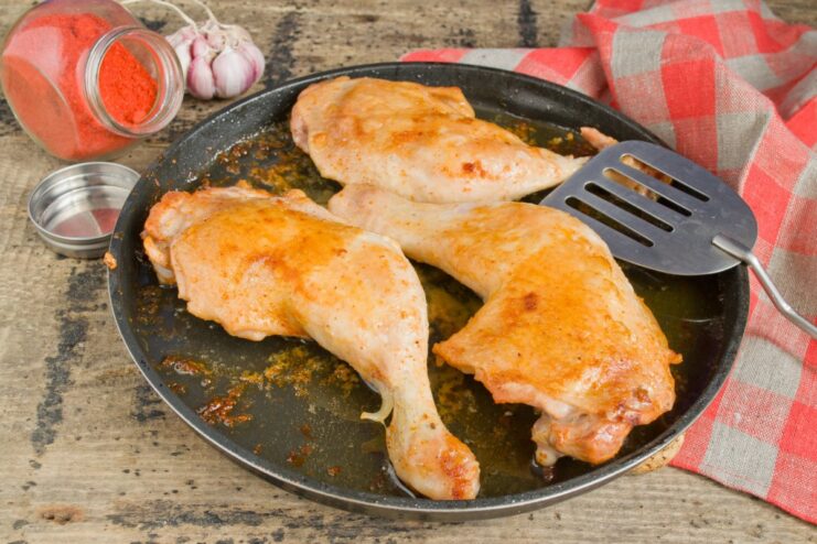 Step 8: Covering the pan to cook the chicken through Frying pan with chicken legs covered with a glass lid to finish cooking.