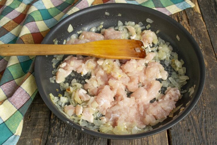 Cooking Diced Chicken with Sautéed Onions Diced chicken fillet being added to a pan with sautéed onions and stirred with a spatula.