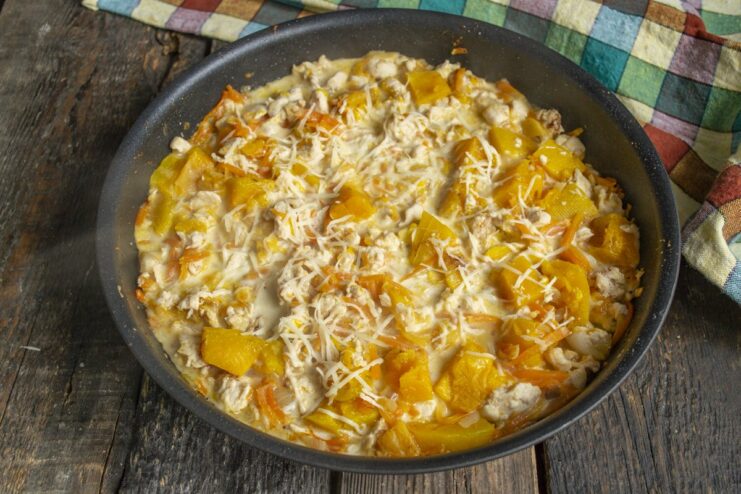 Finishing the Dish with Grated Parmesan Cheese Sprinkling freshly grated Parmesan cheese over the chicken and pumpkin dish in the pan.