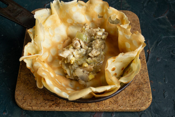 Assembling the layered pie by alternating pancakes and filling.