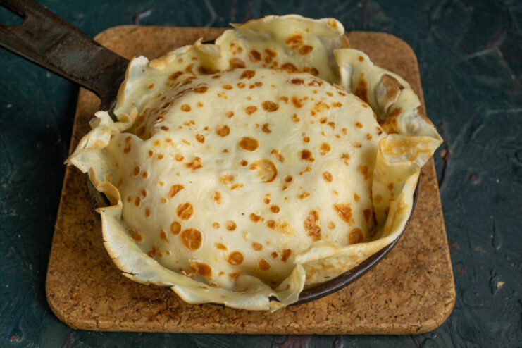 The top of the pie being covered with the final pancake layer.