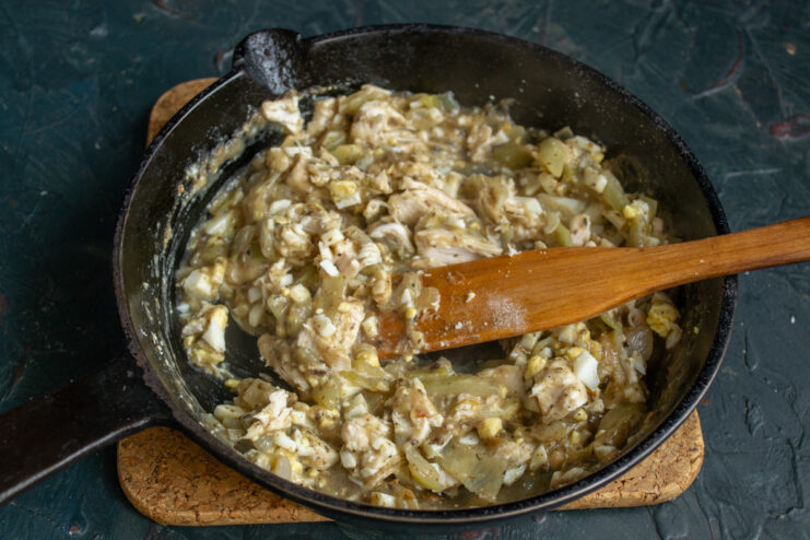 The complete chicken, egg, and mushroom filling being mixed in a pan.