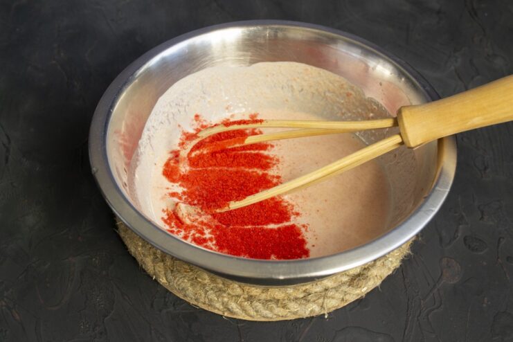 Mixing smetana and tomato puree to create a creamy sauce for the cabbage rolls. A white bowl with a mixture of sour cream and tomato puree for the sauce.