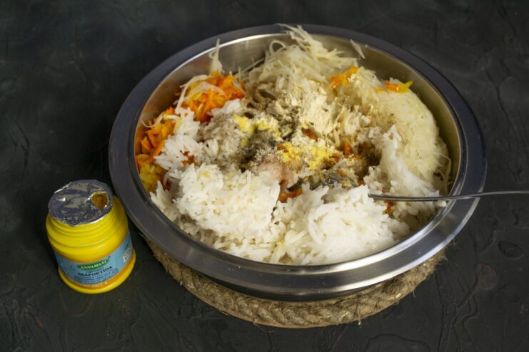 Combining all ingredients for the lazy cabbage roll filling in a large bowl. A large bowl containing minced chicken, rice, sauerkraut, and vegetables for the filling.