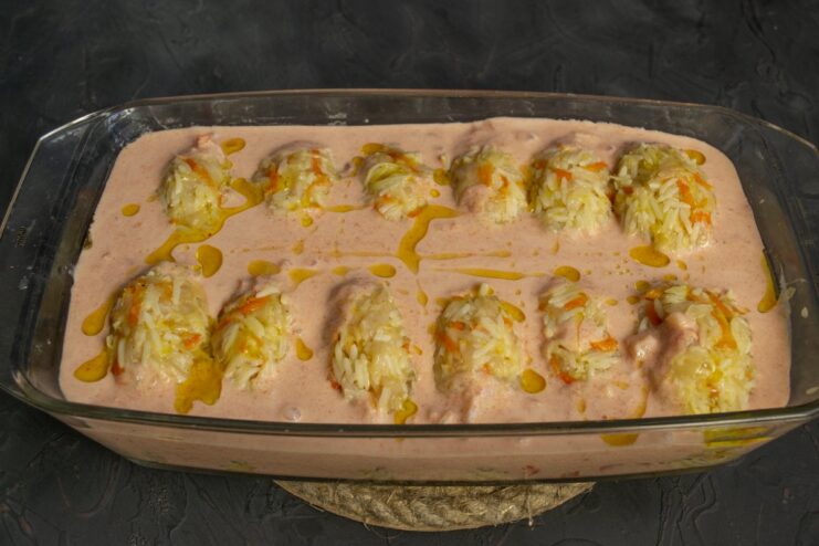 Pouring the creamy tomato sauce over the cabbage rolls before they go into the oven. Pouring smetana-tomato sauce over the lazy cabbage rolls in the baking dish.