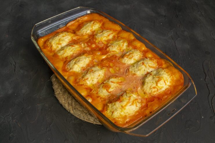 The final baked lazy cabbage rolls, golden and bubbling in the sauce. Baked lazy cabbage rolls with sauerkraut and chicken in a baking dish, fresh from the oven.