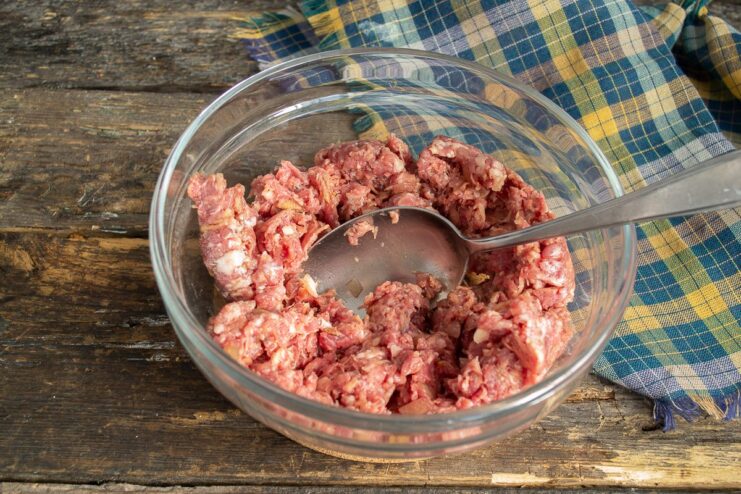 How to Prepare the Perfect Ground Beef Filling for Dumplings A bowl of ground beef mixed with chopped onions and spices for the pelmeni filling.