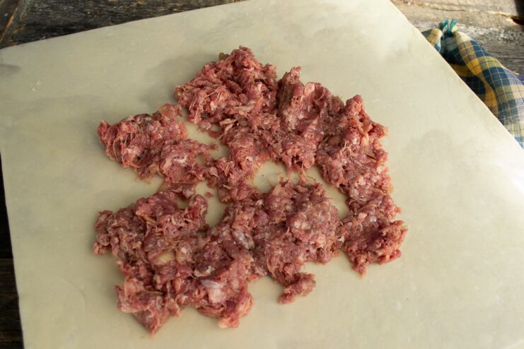 Adding the Beef Filling to the Dough A mound of ground beef filling placed on the center of the rolled-out dough sheet.