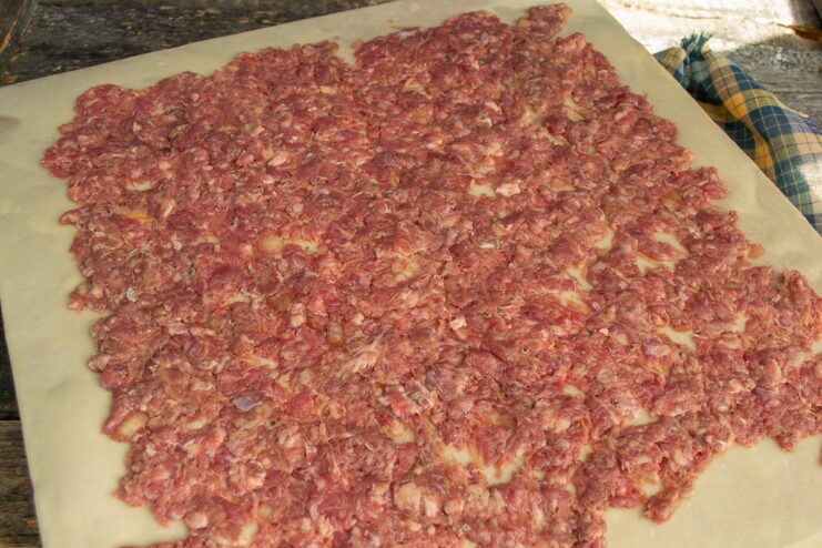 Evenly Spreading the Filling for the Dumpling Roll Ground beef filling spread evenly over the dough, with a clean border around the edges.