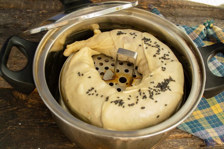 Garnishing with Sesame Seeds Before Steaming The uncooked lazy pelmen in the steamer being sprinkled with black sesame seeds.