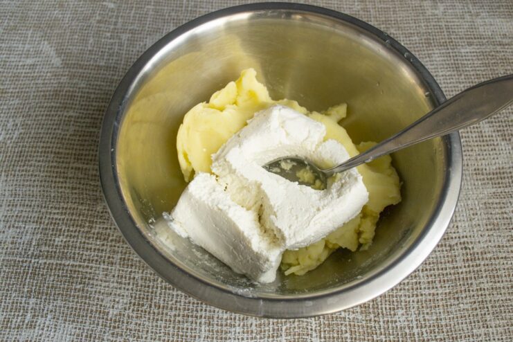Adding a portion of white tvorog to a bowl of mashed potatoes.