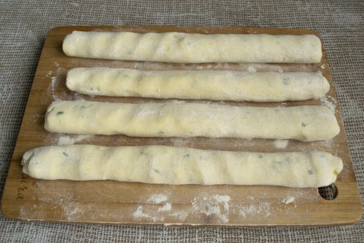 Rolling the potato dough into a long log on a flour-dusted surface.