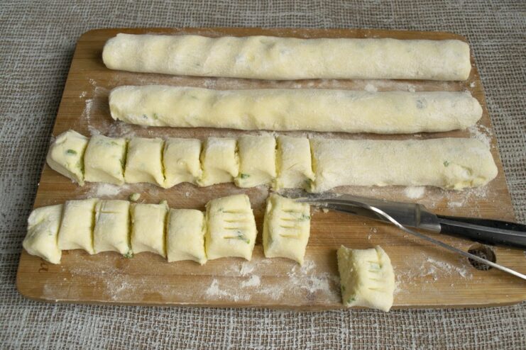 Cutting the dough log into small pieces and pressing them with a fork to create a pattern.