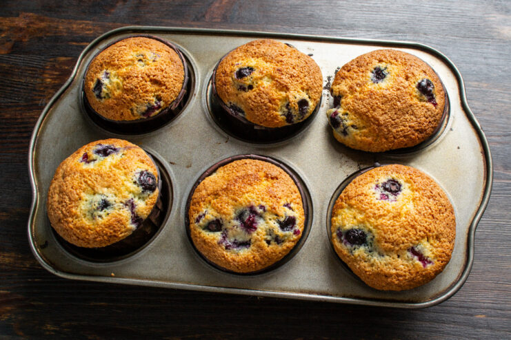 Step 8: Baking the muffins until golden brown A muffin tin with lemon blueberry muffins baking in a hot oven.
