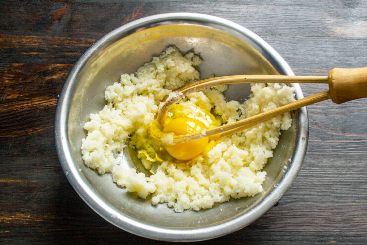 Step 2: Adding an egg to the creamed butter and sugar An egg being cracked into a bowl with a creamed butter and sugar mixture.