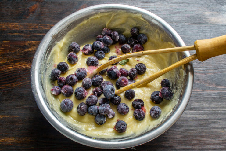 Step 5: Folding in fresh or frozen blueberries A handful of fresh blueberries being added to the lemon muffin batter.