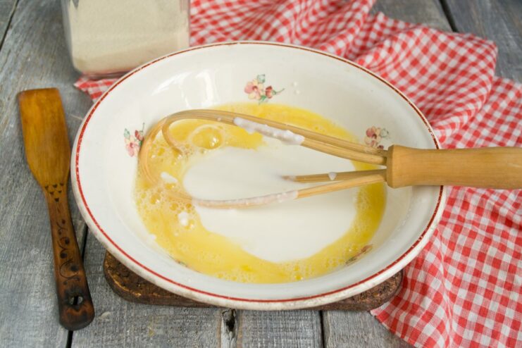Preparing the wet ingredients for the pancake batter Eggs and kefir being whisked together in a glass bowl.