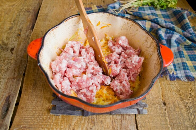 Browning the ground meat with the vegetables to develop a deep, savory flavor. Ground meat being browned and broken up with a spatula in the pot with sautéed vegetables.