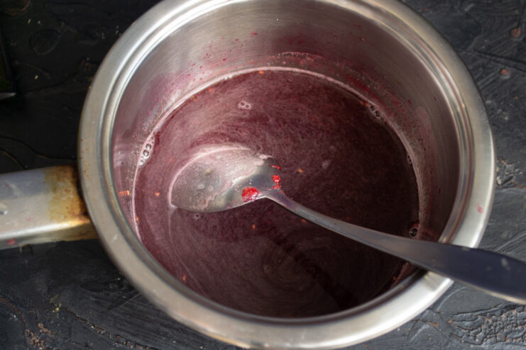 Portioning the jelly mixture for chilling Pouring the liquid raspberry jelly mixture into individual glass dessert bowls.