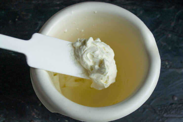 Preparing the whipped cream topping A bowl of heavy cream with a whisk, ready to be whipped, next to a set raspberry jelly.
