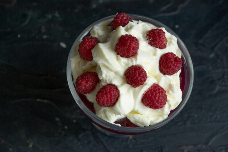 Garnishing with fresh berries for a beautiful finish Fresh raspberries being carefully placed on top of the whipped cream.