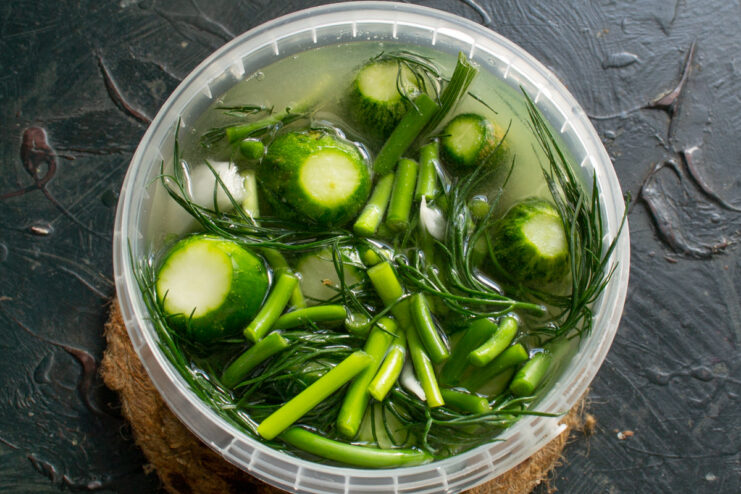 Pouring the Cooled Brine Over the Cucumbers The cooled mustard brine being poured over the cucumbers packed in a container.