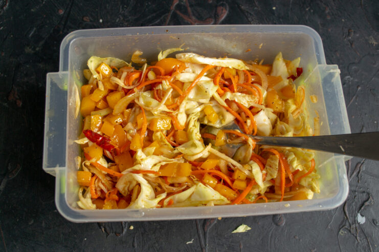A sealed container of vegetables being shaken to mix the marinade.
