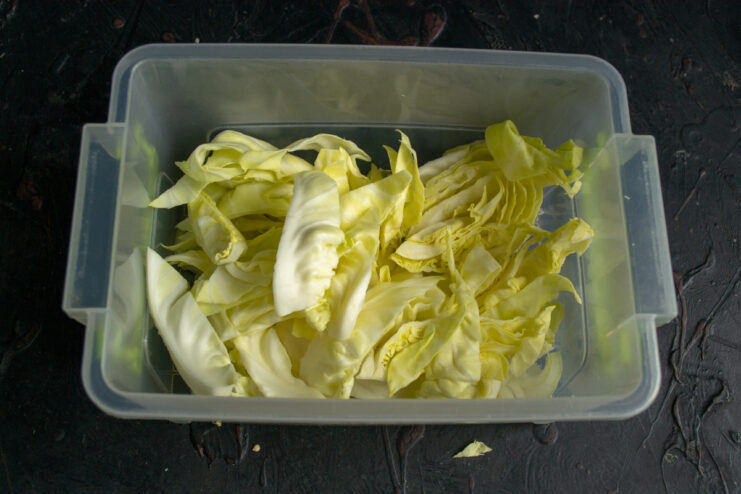 Coarsely chopped white cabbage in a pile on a cutting board.