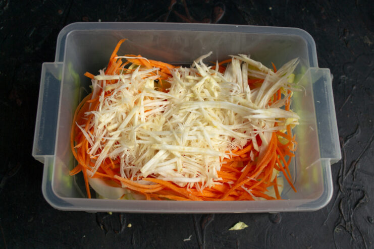 Celery root being sliced into thin strips on a cutting board.