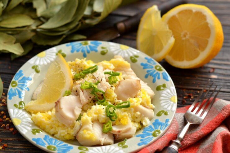 A plate of boiled pollock fillets topped with a rich Polish sauce made with butter and eggs, garnished with green onions.