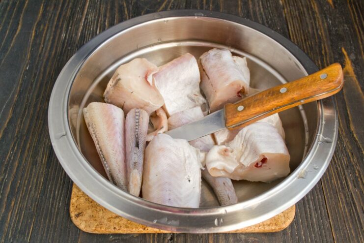 Portioning the Pollock Before Cooking Cleaned pollock fish cut into several steak-like portions on a cutting board.