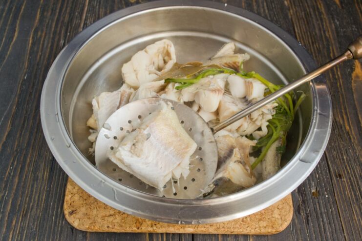 Perfectly Boiled Pollock: The Key to a Tender Texture Pieces of pollock simmering gently in a pot with broth and herbs.
