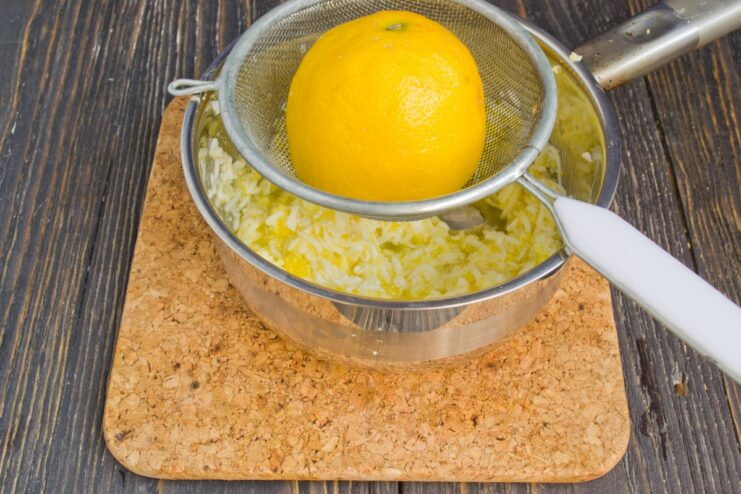 Finishing the Polish Sauce with a Hint of Lemon Squeezing fresh lemon juice into the butter and egg sauce in a saucepan.