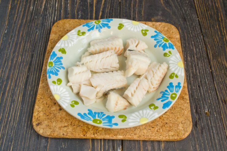 Plating the Tender Boiled Pollock Fillets Flaky, tender pieces of boiled pollock arranged neatly on a white plate.