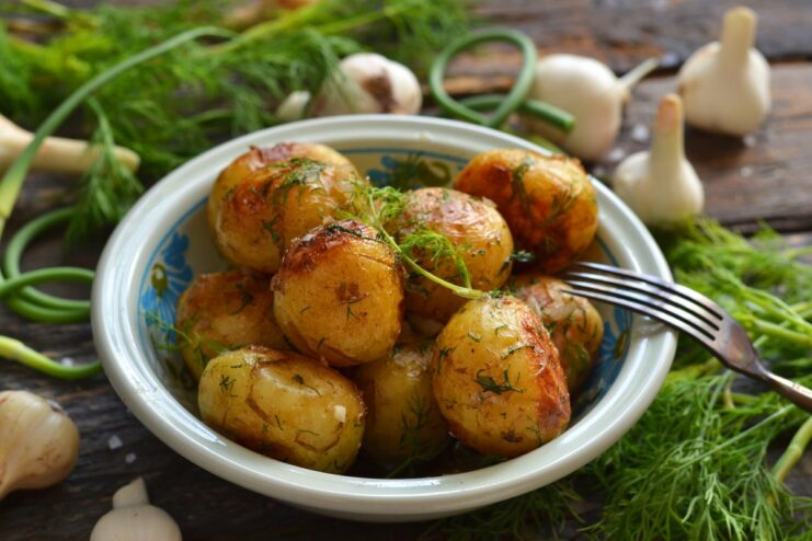 A bowl of golden pan-fried new potatoes garnished with fresh dill.