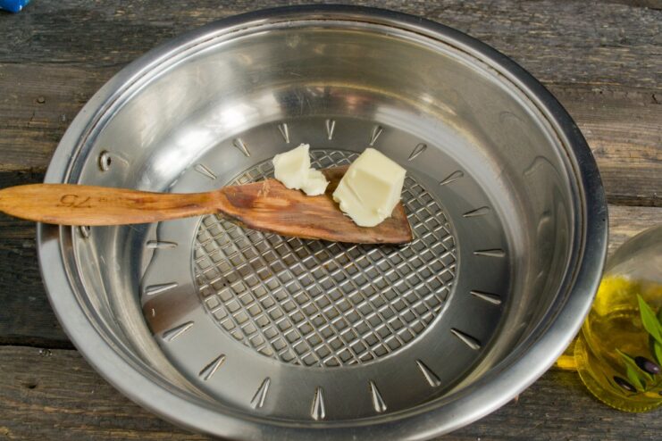 Melting Butter and Oil for Frying Potatoes A pat of butter melting in a frying pan with vegetable oil.