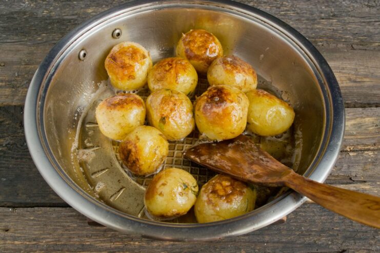 Tossing the Potatoes to Ensure Even Cooking Shaking a frying pan to toss new potatoes for even browning.
