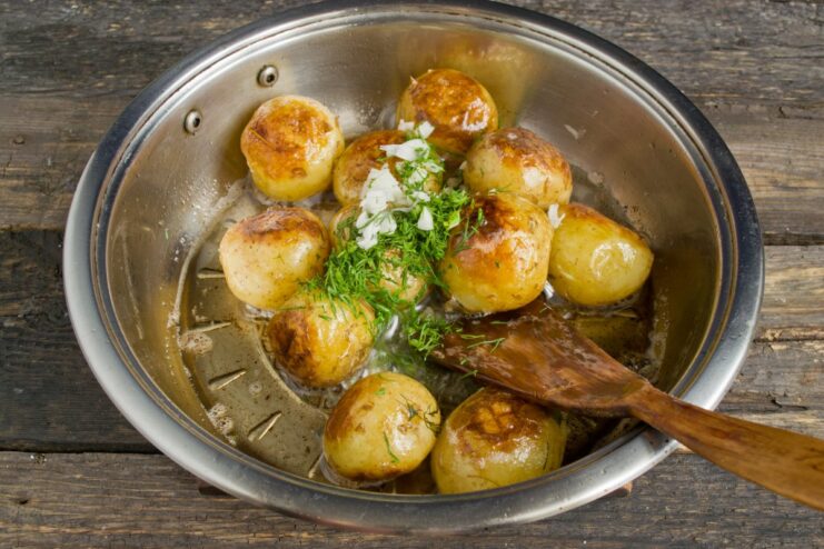 Adding Fresh Dill and Garlic for Flavor Chopped fresh dill and garlic being added to the pan of fried potatoes.