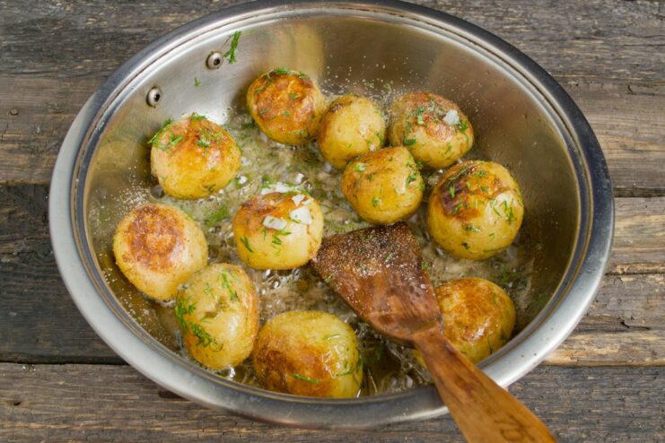 Seasoning the Potatoes and Tossing to Combine Seasoning the pan-fried potatoes with salt and tossing them in the pan.
