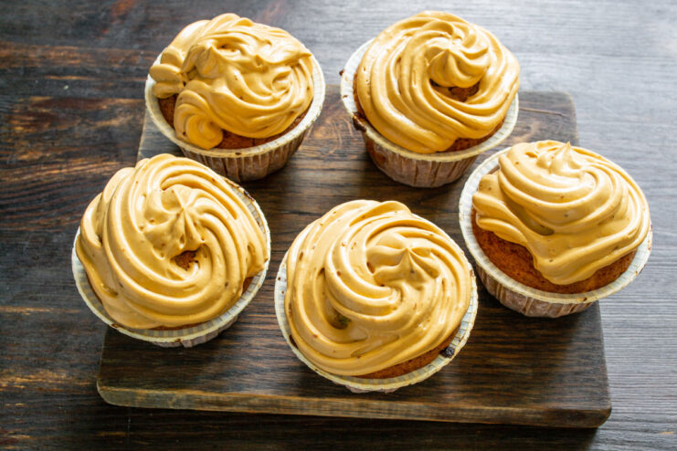 Step 10: Piping Caramel Cream onto the Cooled Cupcakes Piping caramel cream frosting onto cooled carrot cupcakes.