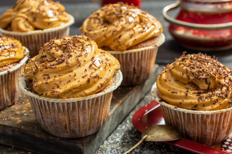 A plate of finished carrot cupcakes with caramel cream, garnished with chocolate shavings.
