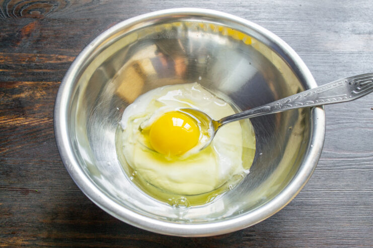Step 1: Combining Smetana and Egg for the Cupcake Batter A bowl with smetana and an egg being mixed with a whisk.
