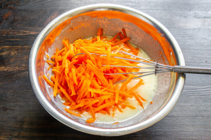 Step 4: Preparing the Freshly Grated Carrots Grating fresh carrots on a coarse grater for the cupcake batter.