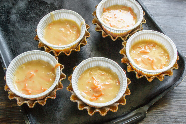 Step 7: Filling the Cupcake Liners with Batter Pouring carrot cupcake batter into paper liners in a muffin tin.